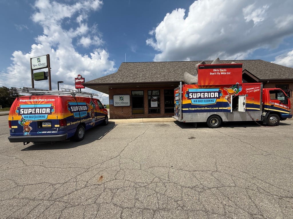 Two Superior Air Duct Cleaning vehicles — the dryer vent cleaning van and a box truck — parked at a commercial building