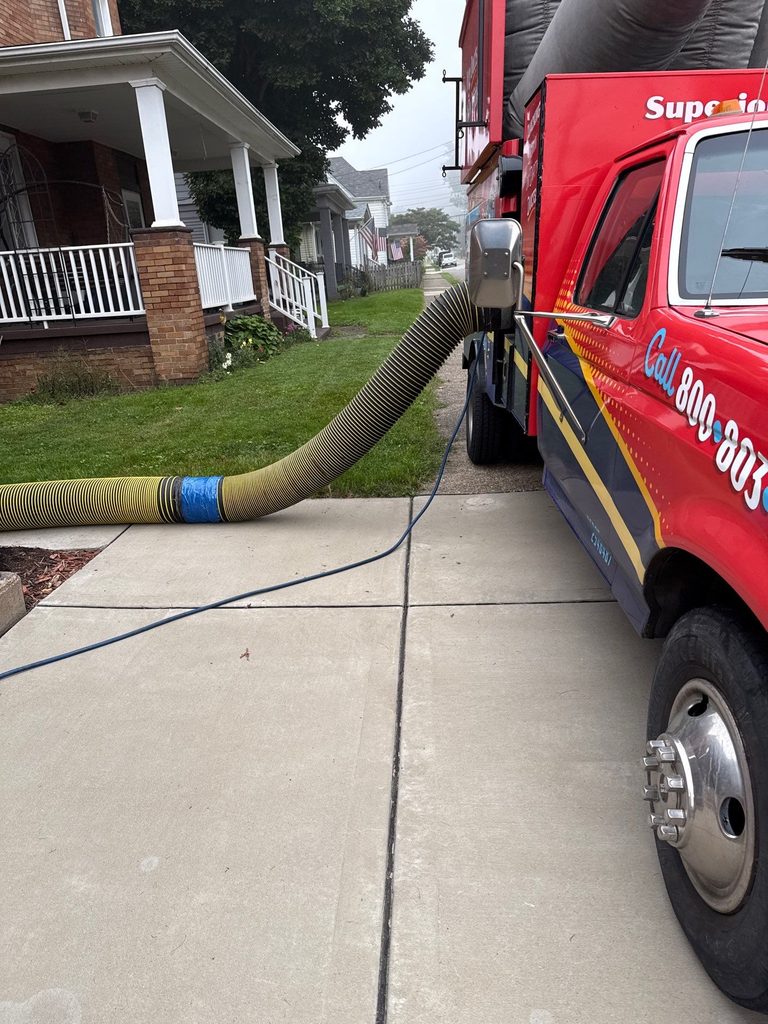 Vacuum hose running from the side of a Superior truck up the walkway to a home's front porch