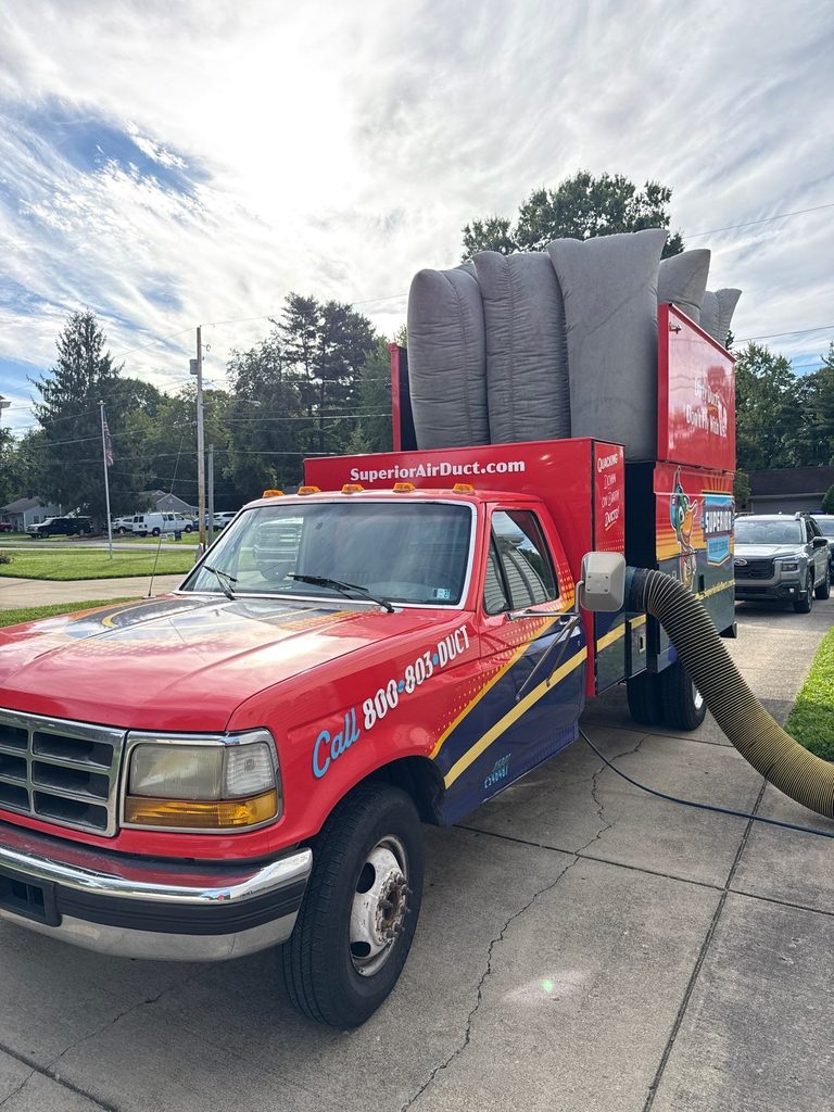 Superior duct-cleaning truck parked on a residential street with the vacuum hose connected and filter bags loaded