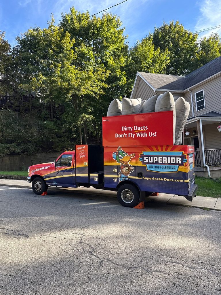 Superior Air Duct Cleaning truck reading 'Dirty Ducts Don't Fly With Us!' parked in front of a home