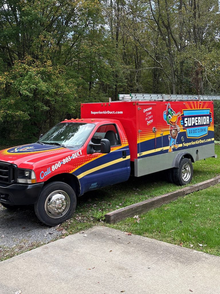 Superior Air Duct Cleaning truck parked in a gravel driveway in front of fall trees