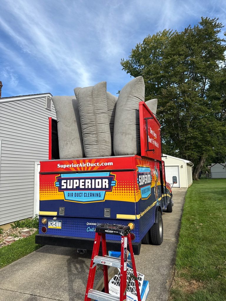 Rear of a Superior Air Duct Cleaning truck in a driveway with a red ladder set up beside it