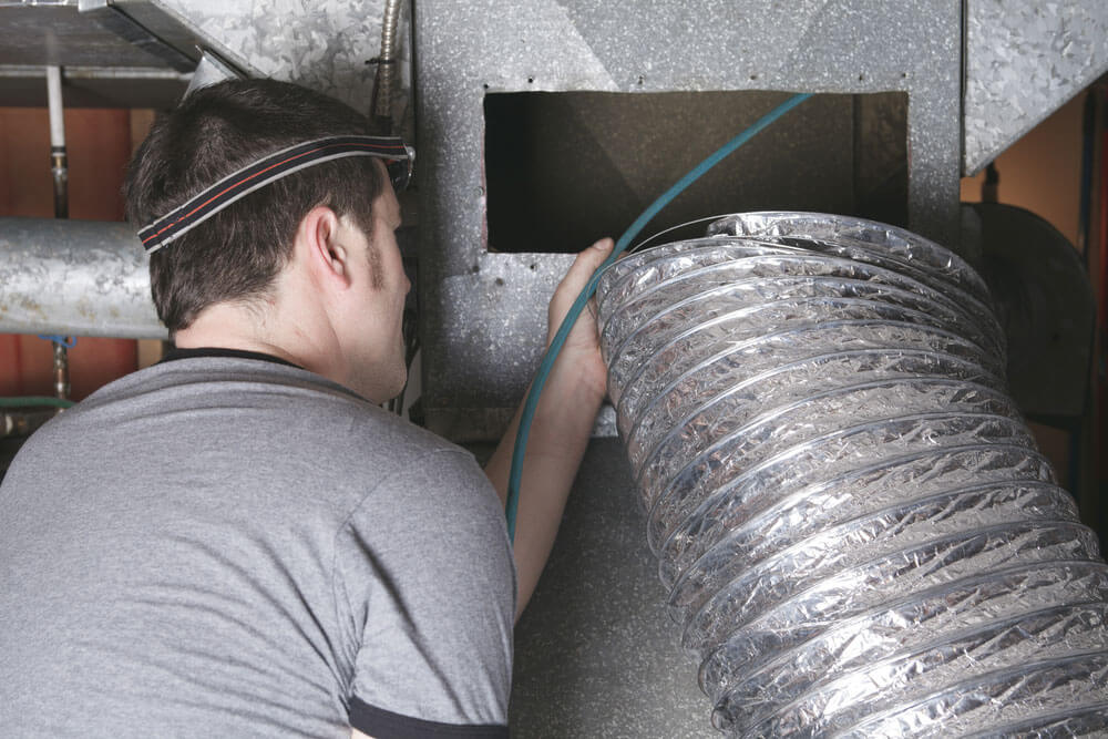 Man in gray shirt installing air duct