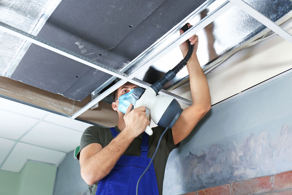 Male technician cleaning industrial air conditioner indoors