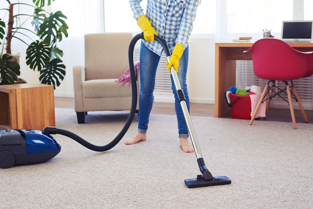 Female cleaning carpet with vacuum cleaner