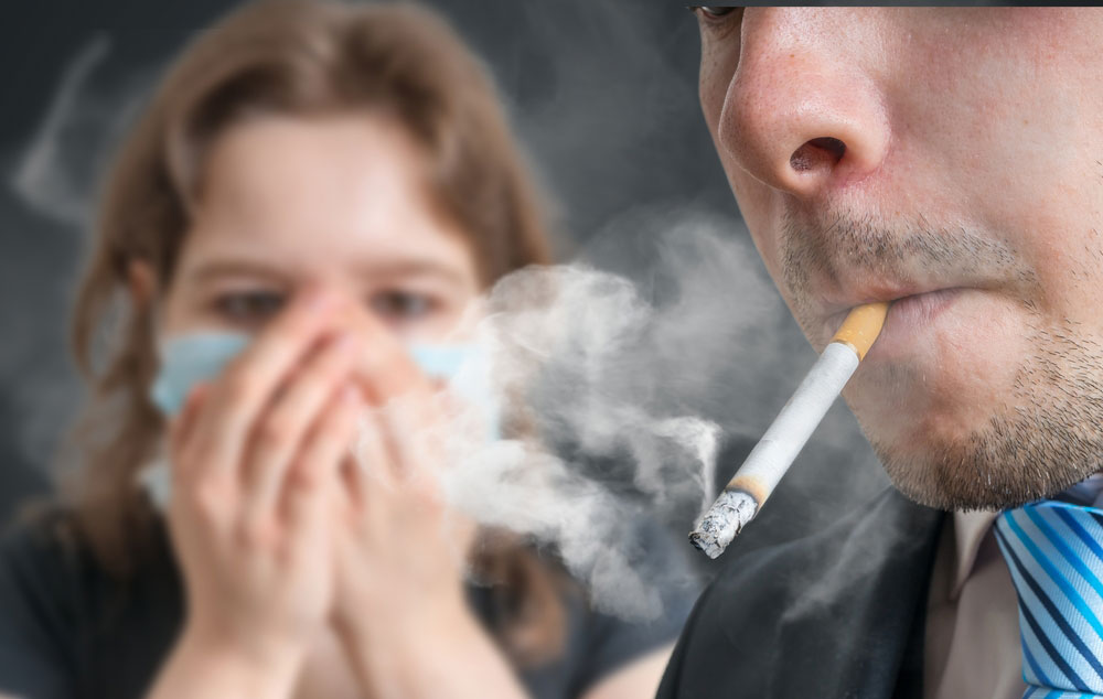 Man smokes a cigarette and a woman covers her face