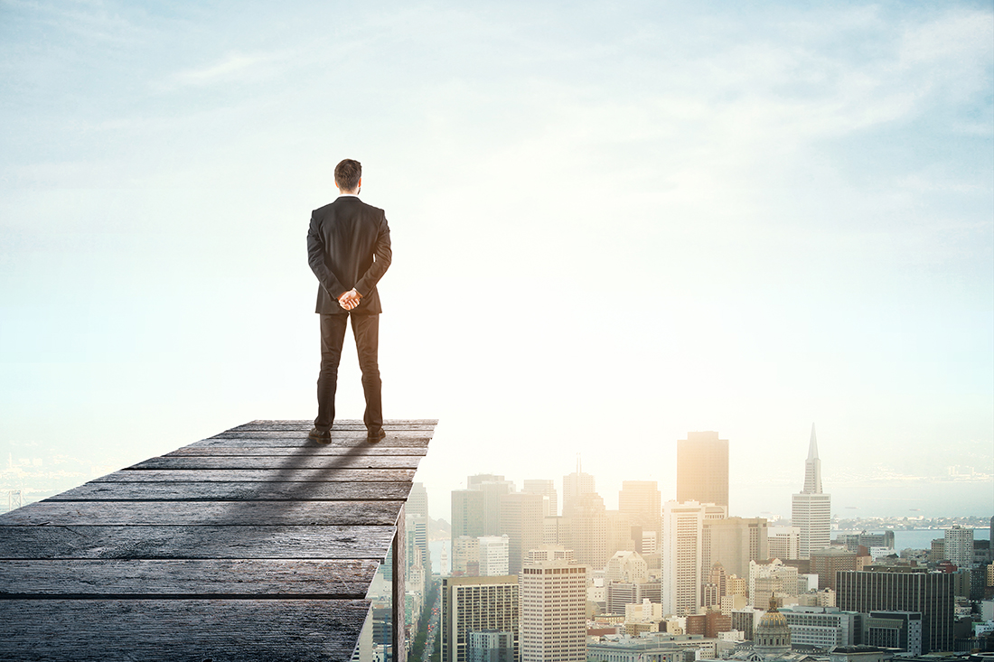 Young businessman on wooden pier looking at city