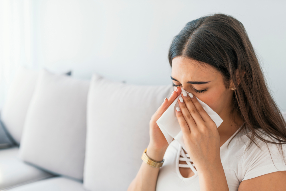 Woman sneezing into tissue