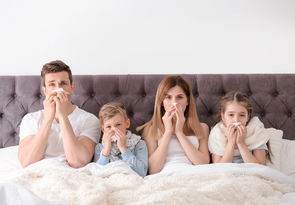 Family of four blowing noses into tissues