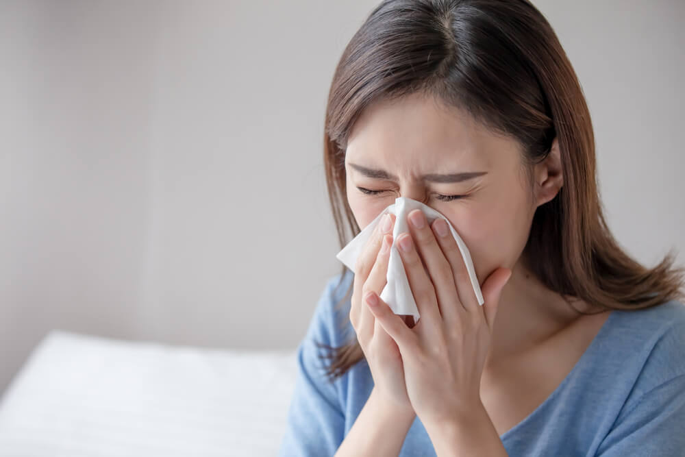 woman sneezing into kleenex