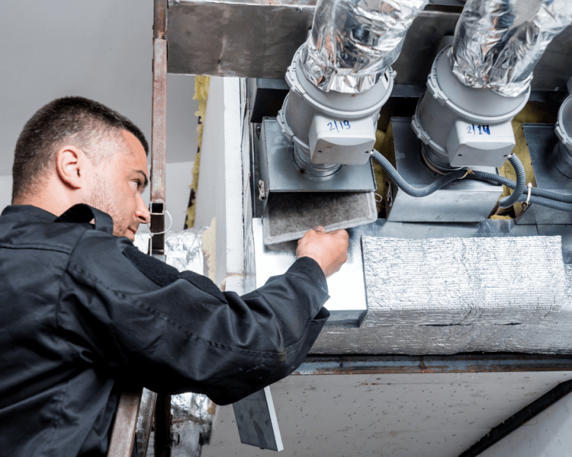 Person changing a dirty air filter in a commercial space