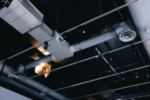 Low angle shot of a metal black ceiling with white ventilation pipes
